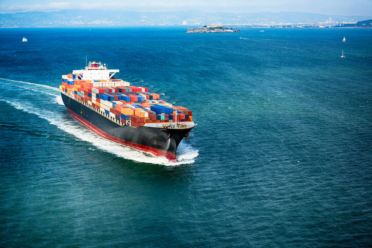 A large container ship sailing on the open ocean under a clear sky.